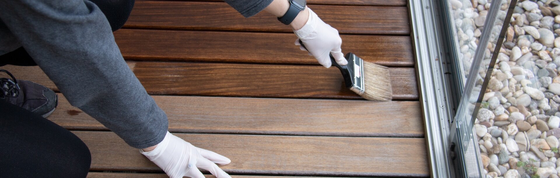 2251442001 | Worker refinishing wood, hand painting wooden deck floor with wood protection oil